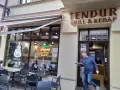 Mężczyzna wychodzi z lokalu "Tendur Grill & Kebap", niosąc talerz. W witrynie neonowy napis "Oryginalny Kebab".