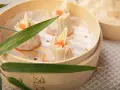 Pierożki dim sum w bambusowym parowniku, ozdobione kawałkiem bambusa i pomarańczowym ikrą.