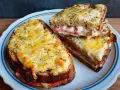 Dwa pyszne croque monsieur z rozpływającym się serem i szynką, posypane ziołami.