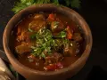 Gulasz z wołowiny w glinianej misie, posypany świeżą pietruszką. Aromatyczne czaszuszuli zachęcają do spróbowania.