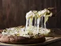Rozpływający się ser z pizzy quattro formaggi ciągnie się w długich nitkach. Pyszny, gorący przysmak.