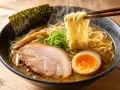 Parujący ramen z makaronem, plastrem wieprzowiny, jajkiem na pół, bambusem i wodorostami nori. Pyszne danie, z czego jest zrobione, widać na talerzu.
