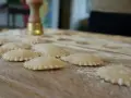 Świeże ravioli na drewnianej desce, posypane mąką. Zastanawiasz się, ravioli z czym podawać?