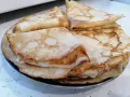 Stos cienkich, złocistych naleśników, idealnych na śniadanie lub deser. Każdy z nich ma delikatne pęcherzyki i lekko przypieczone brzegi.