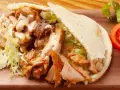Pyszna bułka kebab z soczystym mięsem, chrupiącą sałatą i kremowym sosem. Idealna na szybki lunch.