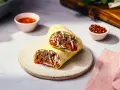 Pyszny rollo z mięsem, warzywami i sosem, podany na talerzu. Obok miseczki z sosem i papryczkami chili.