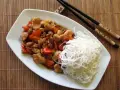 Kurczak kung pao po seczuańsku z orzeszkami ziemnymi i papryką, podany z ryżowym makaronem.