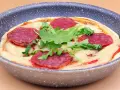 Mini pizza na patelni z serem, rukolą i plasterkami pikantnej salsiccii.