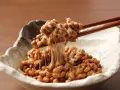 Natto co to? Sfermentowana soja z charakterystyczną, ciągnącą się konsystencją, podana w miseczce, nabierana pałeczkami.