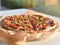Apetyczna pizza Guiseppe 4 sery, z widocznymi kawałkami mięsa, kukurydzy i papryki, leży na papierze do pieczenia.
