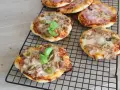 Kilka pysznych pizzett z tuńczykiem, oliwkami i bazylią na czarnej kratce.