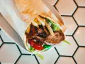 Pyszny kebab z mięsem, frytkami, warzywami i sosem. Zastanawiasz się, ile kcal ma kebab? Ten wygląda na sycący!