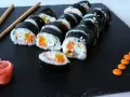 Rząd hosomaki surimi z marchewką i żółtą papryką, podane z imbirem i pomarańczowym sosem.