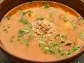 Aromatic gruzińska zupa charczo w glinianej misce, ozdobiona posiekanymi orzechami i świeżą kolendrą.