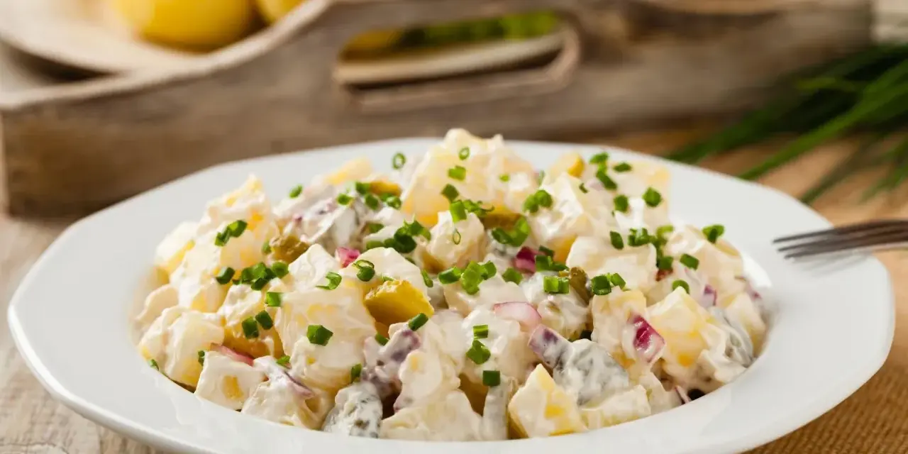 Pyszna, oryginalna kartoffelsalat z ziemniaków, ogórków kiszonych i cebuli, posypana szczypiorkiem.
