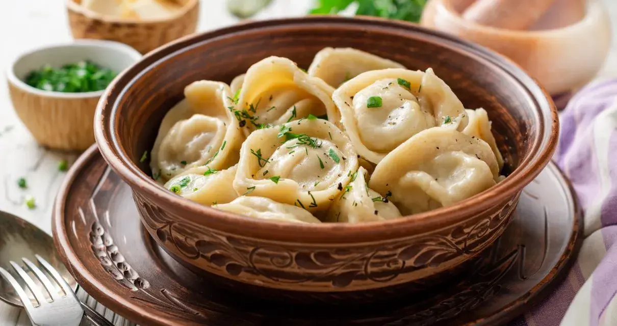 Pielmieni co to? Pyszne, domowe pierożki z mięsem, posypane świeżym koperkiem, w glinianej misce.