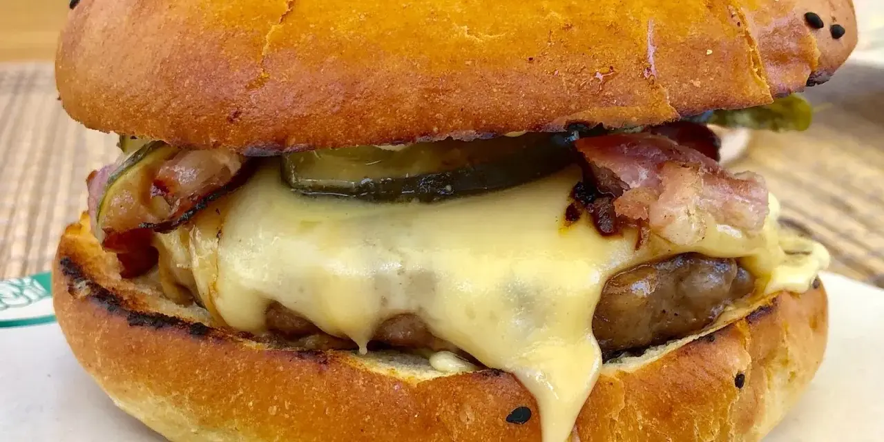 Pyszny burger z dzika z rozpływającym się serem, chrupiącym boczkiem i piklami. Idealny na leśną ucztę!