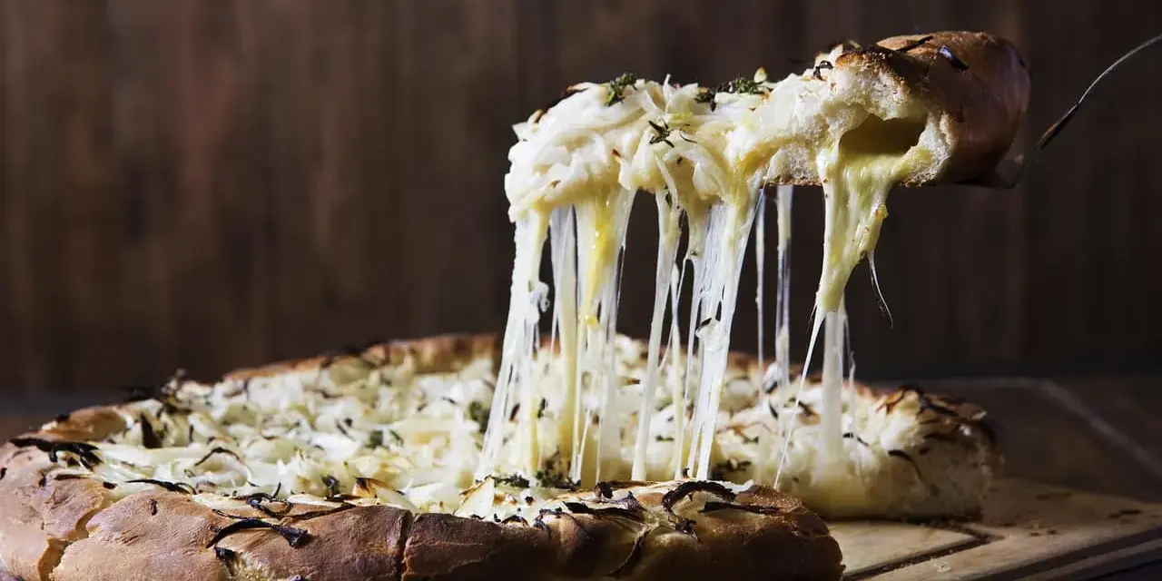 Rozpływający się ser z pizzy quattro formaggi ciągnie się w długich nitkach. Pyszny, gorący przysmak.