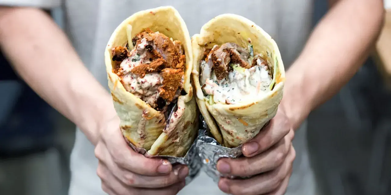 Dwie porcje pysznego, soczystego kebab na cienkim, zawinięte w tortillę, z sosem i warzywami.