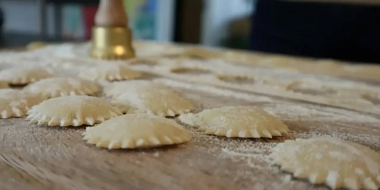 Ravioli co to? Świeżo przygotowane pierożki z ciasta makaronowego, posypane mąką, czekają na gotowanie.