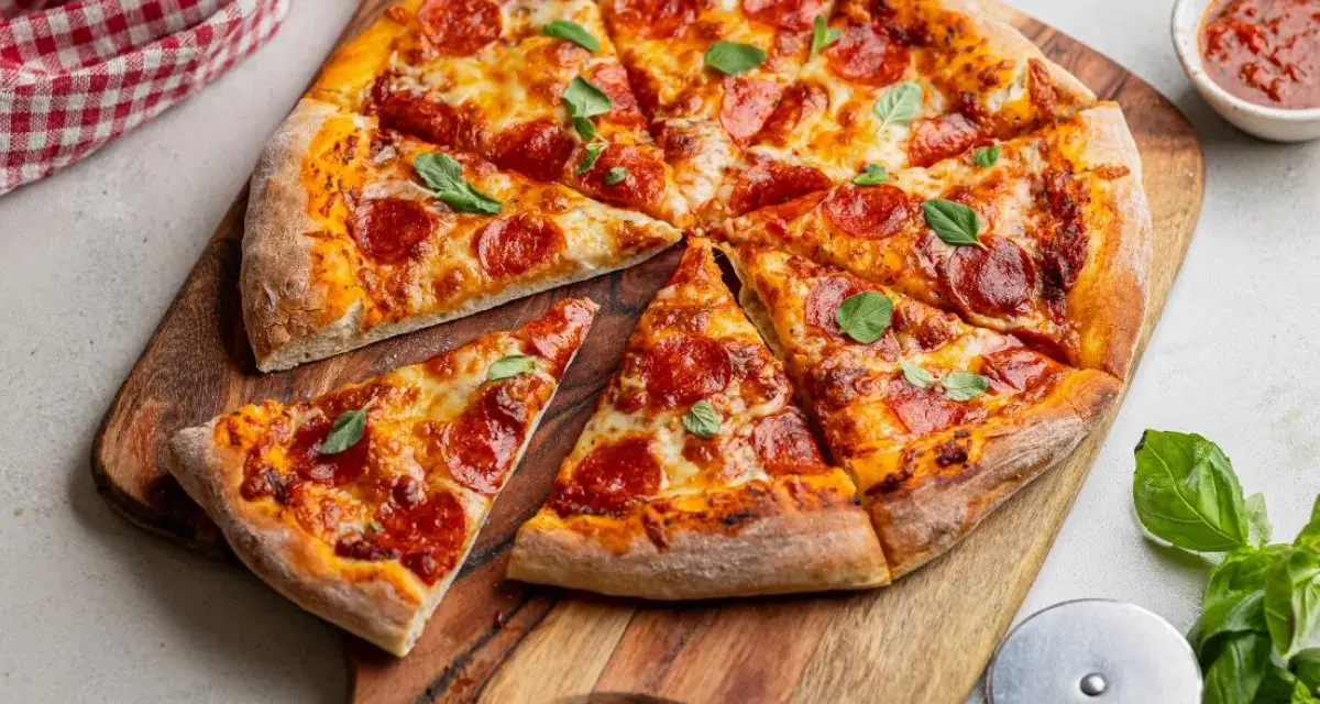 Apetyczna pizza pepperoni z ciągnącym się serem i świeżą bazylią, gotowa do podania.