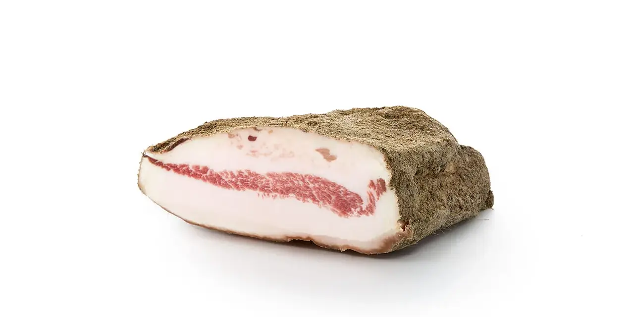 Kawałek guanciale z widocznym pasmem czerwonego mięsa i białej słoniny, otoczony przyprawami.