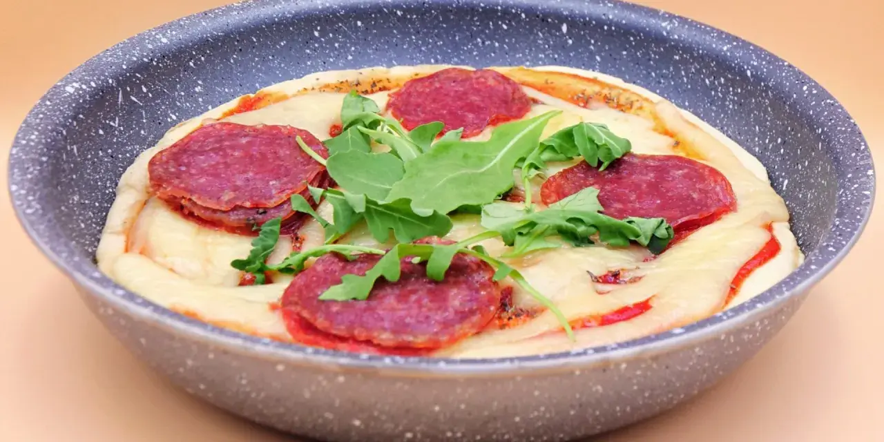 Mini pizza na patelni z serem, rukolą i plasterkami pikantnej salsiccii.