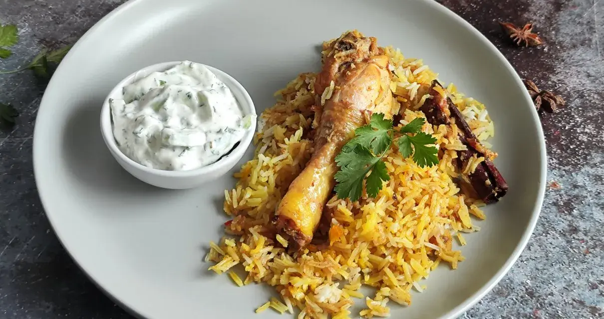 Pyszny kurczak biryani z ryżem, jogurtowym dipem i przyprawami.