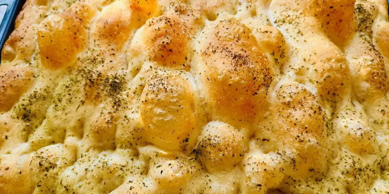 Chrupiąca pizza focaccia z ziołami, świeżo wyjęta z pieca. Idealna na przekąskę.