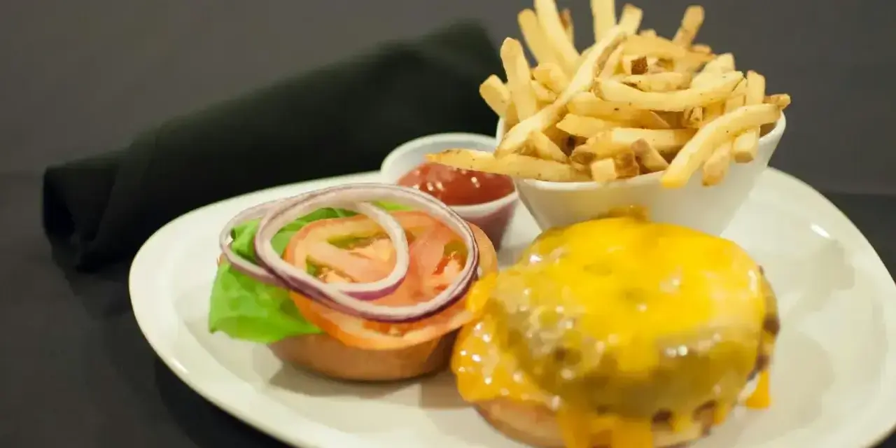 Talerz z hamburgerem, frytkami i ketchupem.