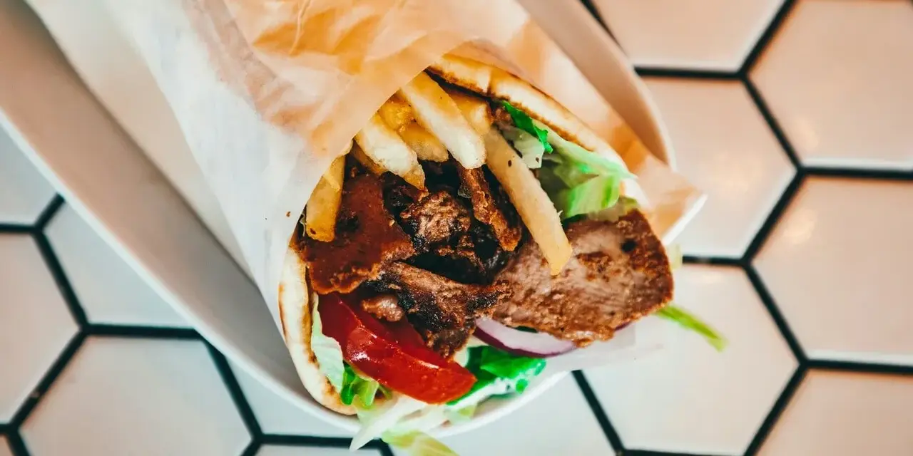 Pyszny kebab z mięsem, frytkami, warzywami i sosem. Zastanawiasz się, ile kcal ma kebab? Ten wygląda na sycący!