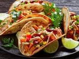 Pyszne meksykańskie jedzenie: tacos z kurczakiem, fasolą, kukurydzą i papryką, podane z limonką i kolendrą.
