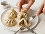 Ręce kroją chinkali, pokazując soczyste nadzienie. Tak się je chinkali, by delektować się każdym kęsem.