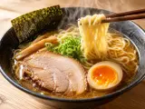 Parujący ramen z makaronem, plastrem wieprzowiny, jajkiem na pół, bambusem i wodorostami nori. Pyszne danie, z czego jest zrobione, widać na talerzu.