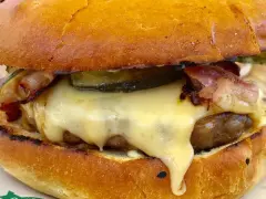 Pyszny burger z dzika z rozpływającym się serem, chrupiącym boczkiem i piklami. Idealny na leśną ucztę!