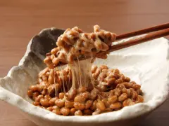 Natto co to? Sfermentowana soja z charakterystyczną, ciągnącą się konsystencją, podana w miseczce, nabierana pałeczkami.