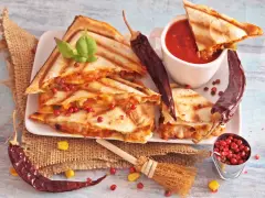 Pyszna quesadilla z serem i papryczkami chili, podana z sosem pomidorowym i ziarnami pieprzu.