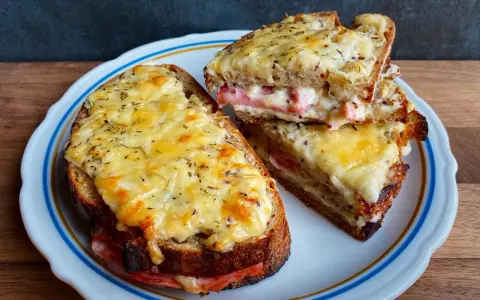 Dwa pyszne croque monsieur z rozpływającym się serem i szynką, posypane ziołami.