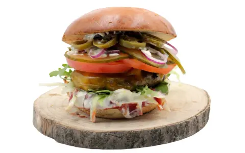 Pikantny jalapeno burger z pomidorem, cebulą i sałatą na drewnianym krążku. Zastanawiasz się nad jego kcal?