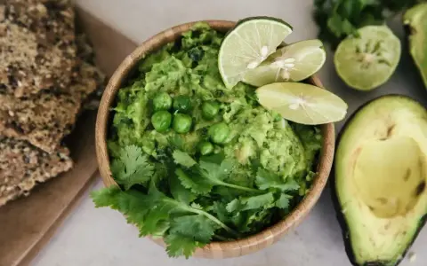 Pyszne guacamole co to? Kremowy dip z awokado, groszkiem, kolendrą i limonką, podany z chrupkimi krakersami.
