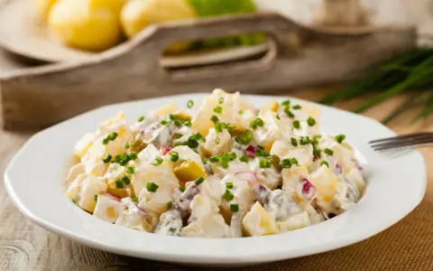 Pyszna, oryginalna kartoffelsalat z ziemniaków, ogórków kiszonych i cebuli, posypana szczypiorkiem.