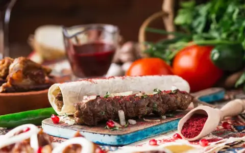 Pyszny gruziński kebab zawinięty w lawasz, posypany sumakiem i ziołami, z dodatkami warzyw i sosu.