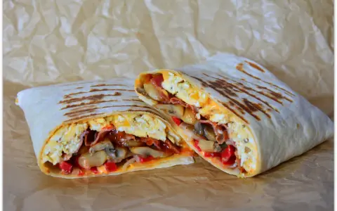 Pyszny wrap jajeczny z boczkiem, pieczarkami i papryką, idealny na śniadanie.