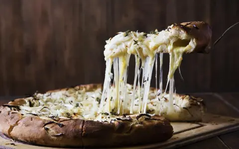 Rozpływający się ser z pizzy quattro formaggi ciągnie się w długich nitkach. Pyszny, gorący przysmak.