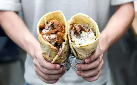 Dwie porcje pysznego, soczystego kebab na cienkim, zawinięte w tortillę, z sosem i warzywami.