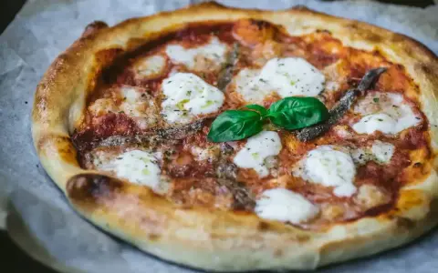 Pyszna pizza z anchois, mozzarellą i bazylią. Jeden z wielu pysznych rodzajów pizzy, idealna na każdą okazję.