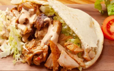 Pyszna bułka kebab z soczystym mięsem, chrupiącą sałatą i kremowym sosem. Idealna na szybki lunch.