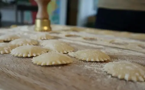 Ravioli co to? Świeżo przygotowane pierożki z ciasta makaronowego, posypane mąką, czekają na gotowanie.