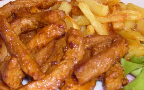 Pyszny gyros wieprzowy w sosie, podany z chrupiącymi frytkami i świeżą sałatą. Idealny posiłek dla każdego miłośnika mięsa.