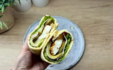 Pyszny wrap wege z serem halloumi, sałatą, ogórkiem kiszonym i oliwkami. Idealny na szybki lunch.